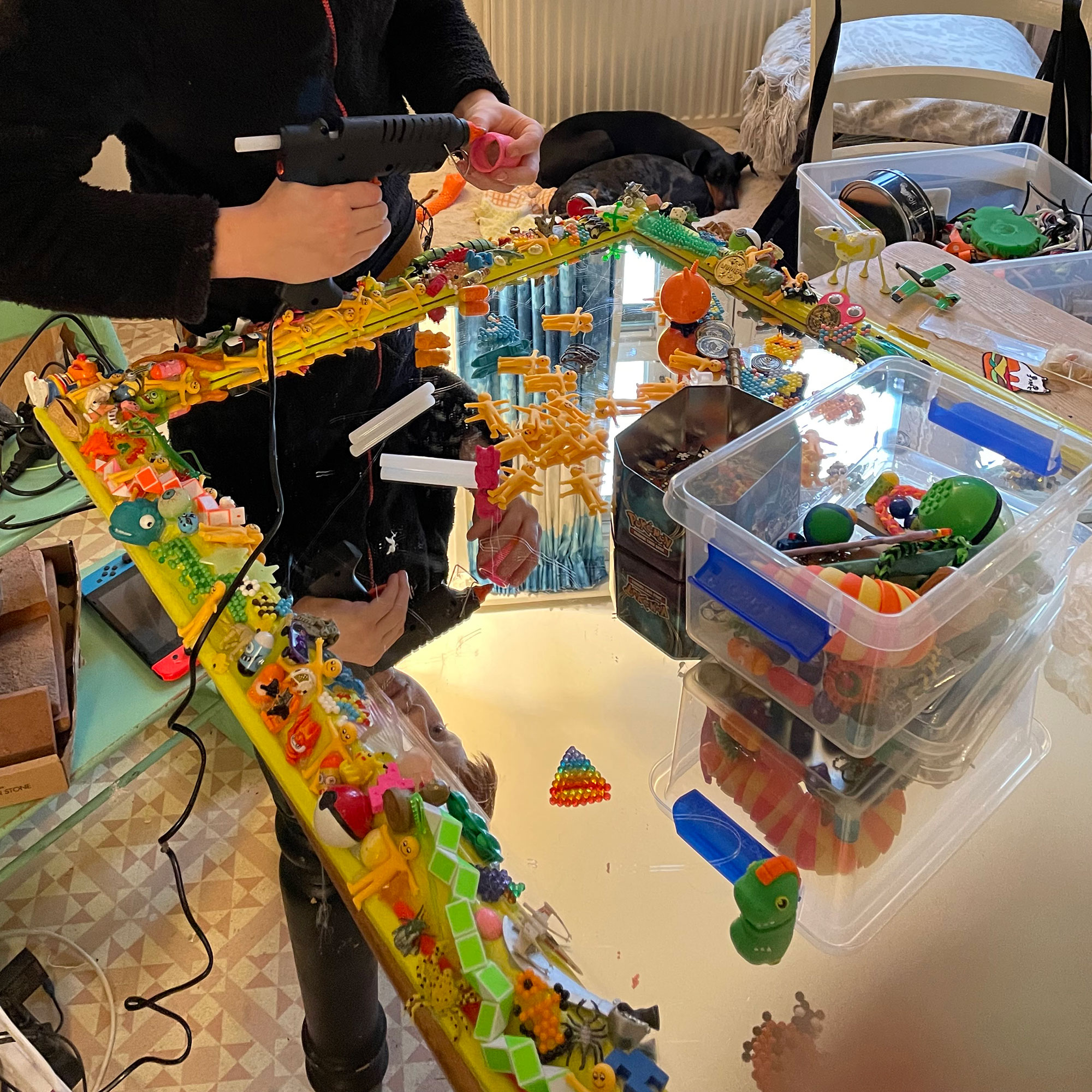 Young boy crafting mirror crafting by attaching old toys