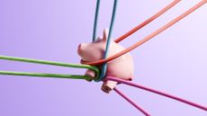 A piggy bank is tangled up in ropes of multiple colors.
