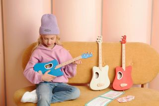 Young girl holding blue Tri-Pop guitar - 3 colors to choose from with chords cards and course books