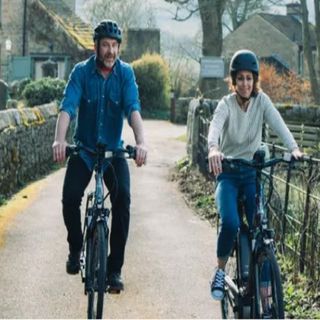 A man and woman cycling along a country path