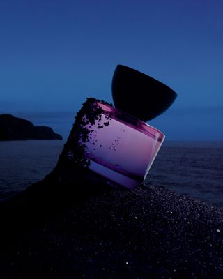 Photograph by Igor Pjoort from Vyrao's Witchy Woo campaign showing purple bottle in black sand