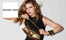 Michael Kors logo placed over an image of a model posing with a gold bag 