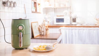 Air fryer on kitchen counter with microwave in background