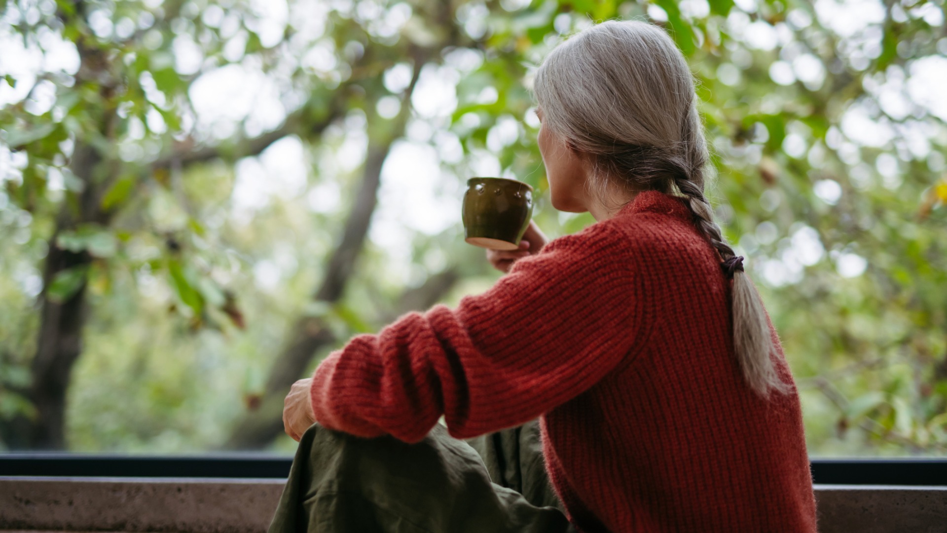 Woman having a drink looking out of a window