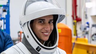 jasmin moghbeli in a spacesuit looking at camera and smiling