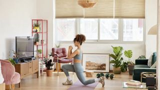 Young woman doing reverse lunge in living room