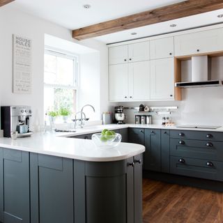 U-shaped kitchen with rounded edges, green-blue cabinetry and wooden beam