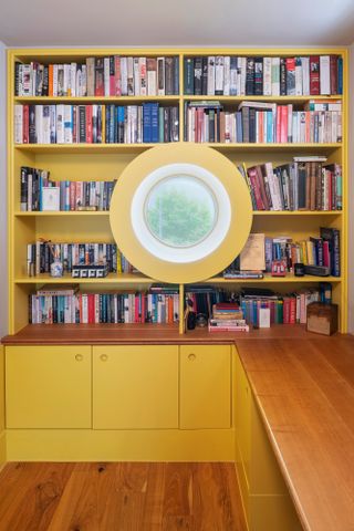 Yellow bookshelves with porthole window at the center