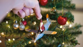 Hand placing Santa in a plane Christmas decoration on a Christmas tree