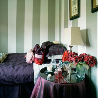 green striped wallpaper and a double bed with bedside table