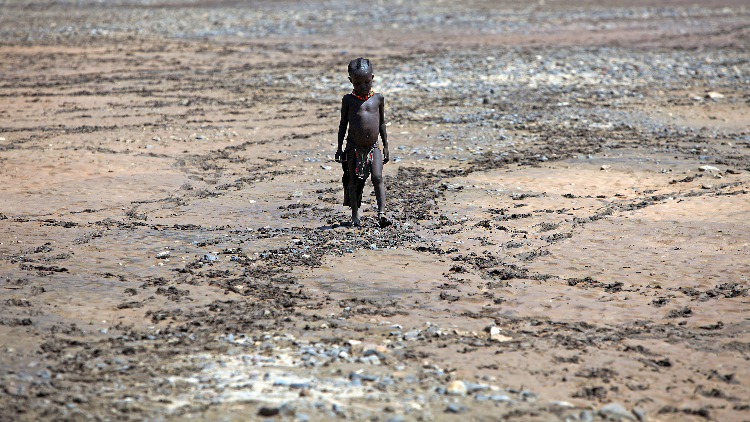 A boy from Northern Kenya's Turkana tribe walks across a dried up river bed. Over 23 million people in east Africa face critical shortages of water and food.