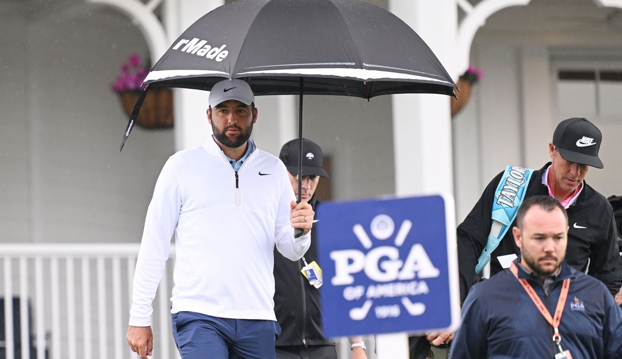 Scottie Scheffler walks under an umbrella