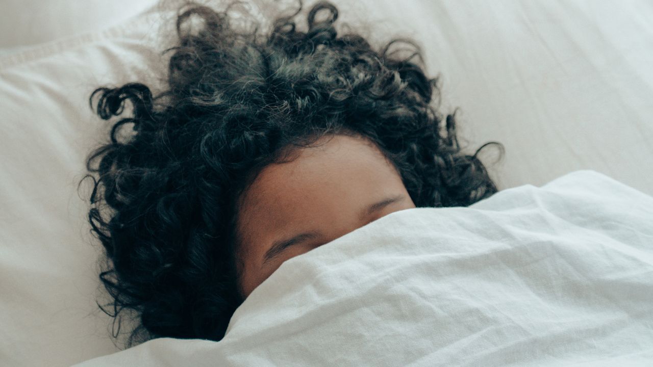 Woman with duvet pulled over her face