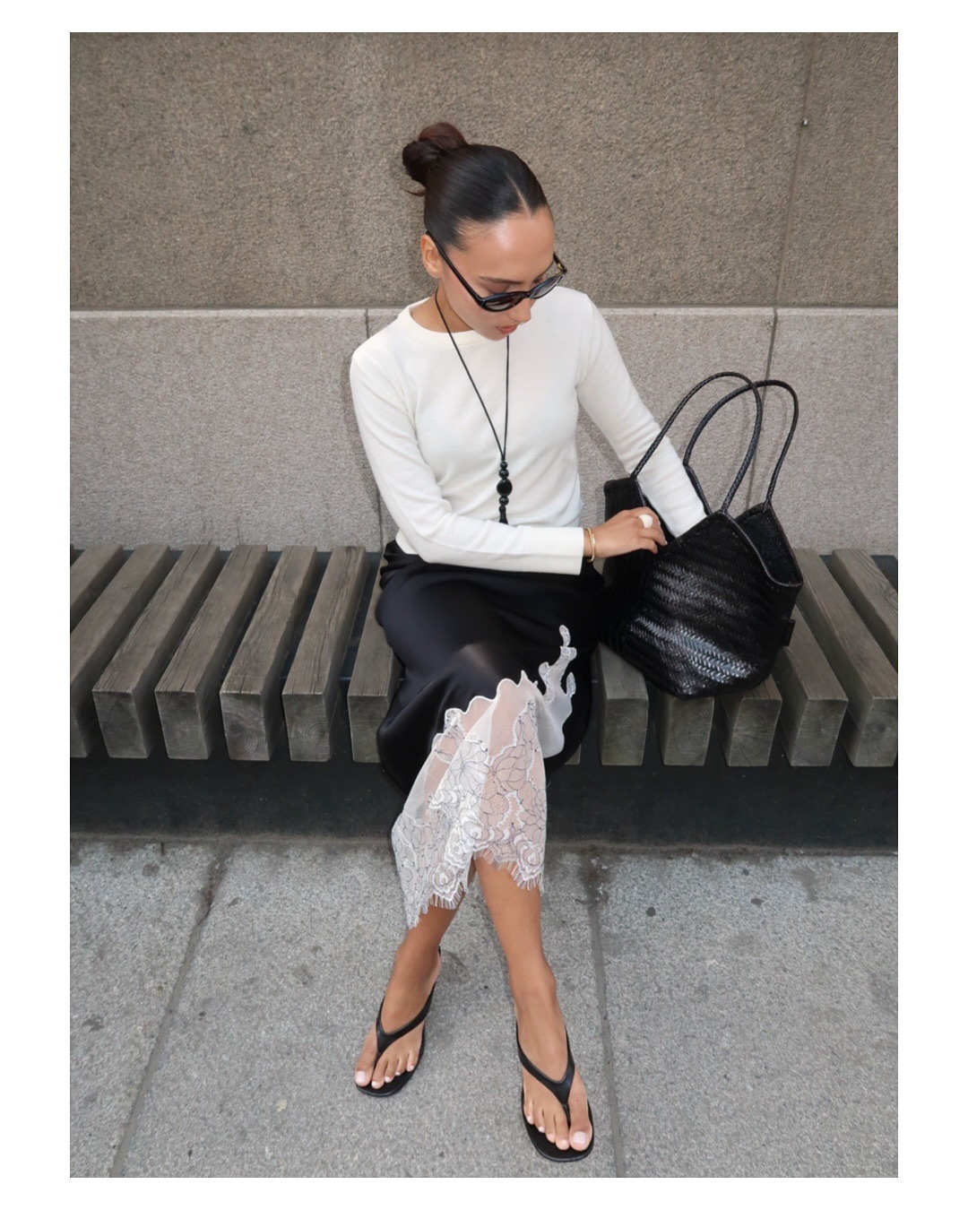 Woman in sweater, silk lace skirt, and thong sandals.