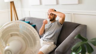 Sweating man drinking water in front of a fan