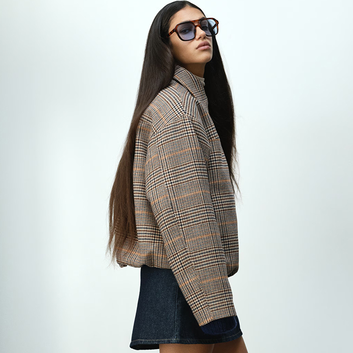 H&M models pose. One model wears long sleeve ruched top. The other model is wearing a versatile bomber jacket with mini skirt. 