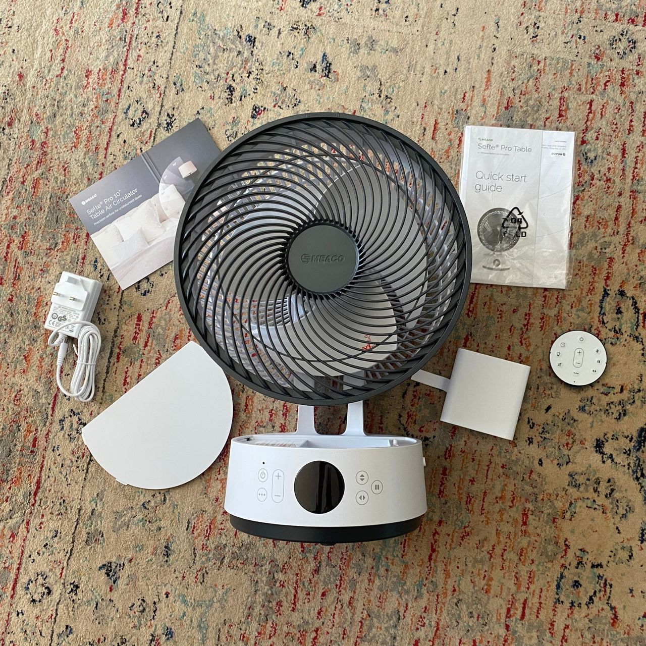 Flat lay of everything you get in the box of the Meaco Sefte Pro table top air circulator on a patterned rug