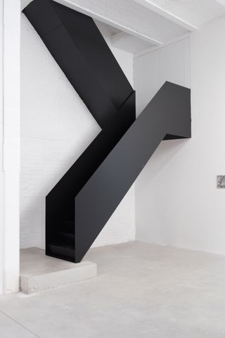 The angular black steel staircase connecting the ground and first floors of Studio Khachatryan's new all-white Brussels space