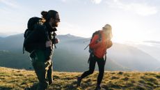 A man and woman hiking up on the hills in the sun