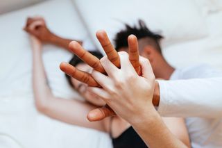 close up of couple on bed with hands blocking camera