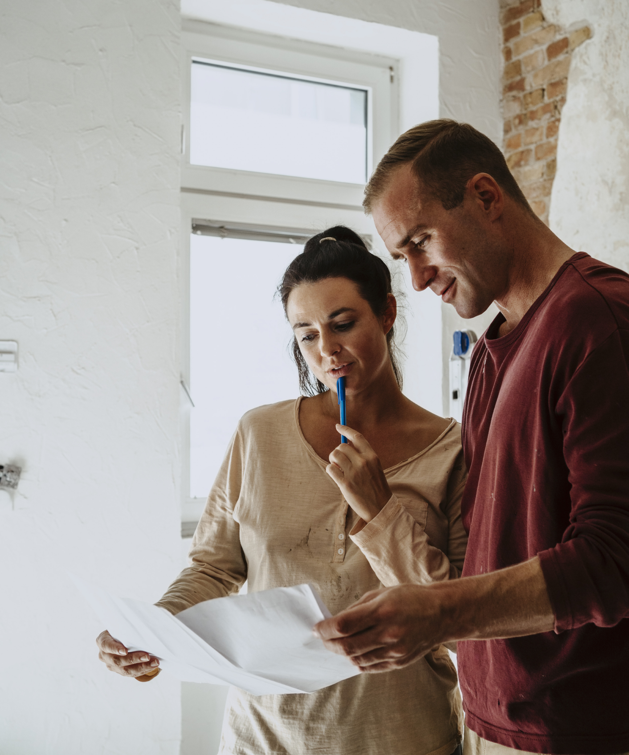 couple looking at piece of paper in house being renovated