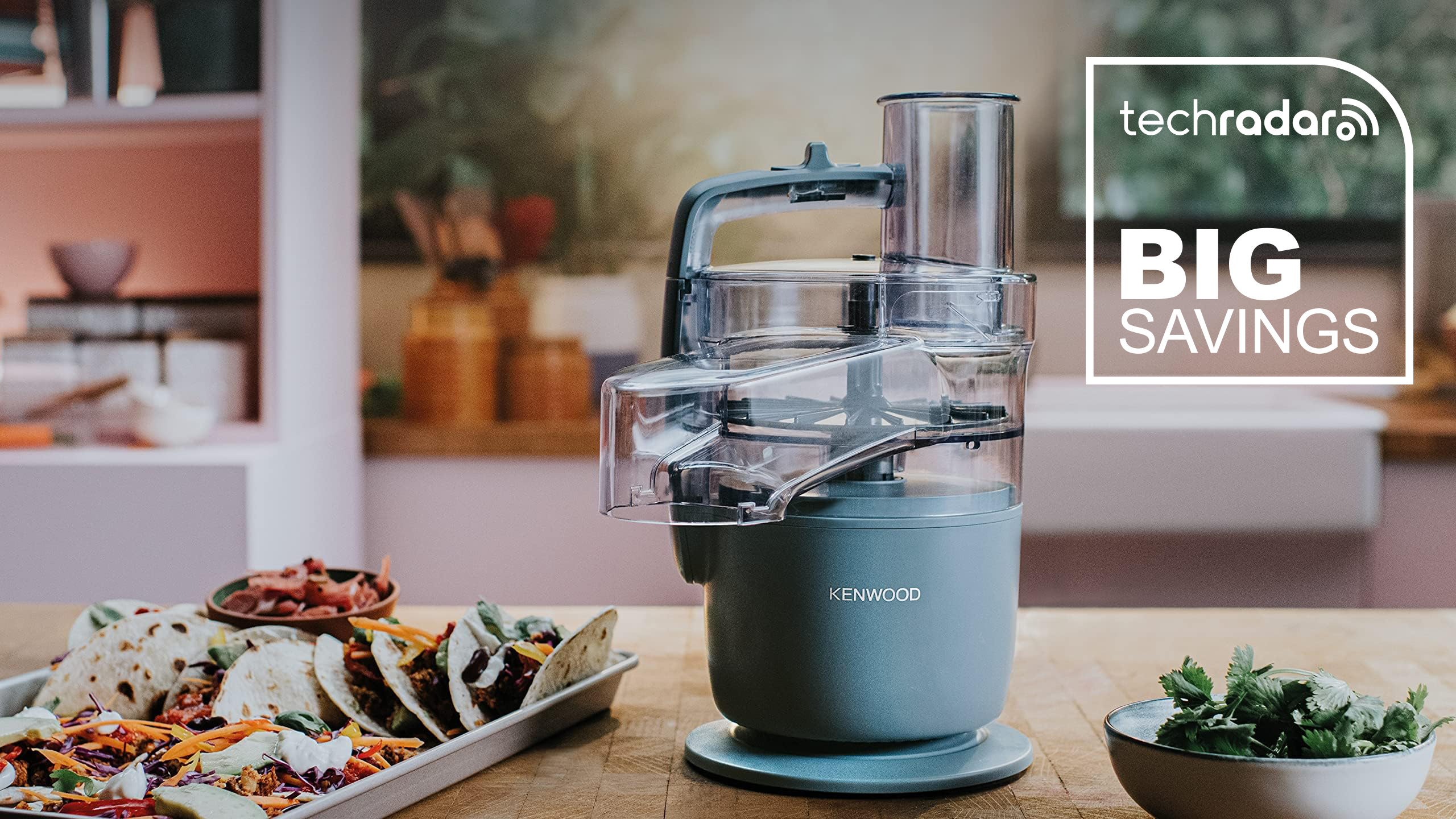 Kenwood MultiPro Go food processor in blue on a table. beside a tray of food with a TechRadar deal logo for big savings
