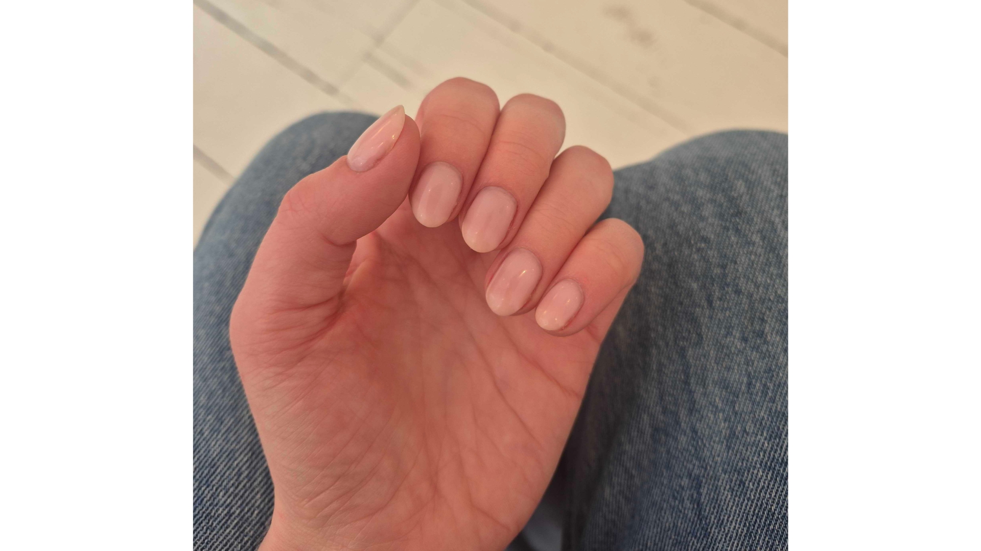 A close-up of Digital Beauty Writer, Naomi Jamieson's pink nails, taken in front of a white wood-floor background