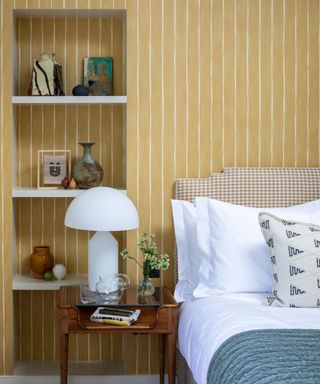 Yellow bedroom with alcove shelving beside the bed