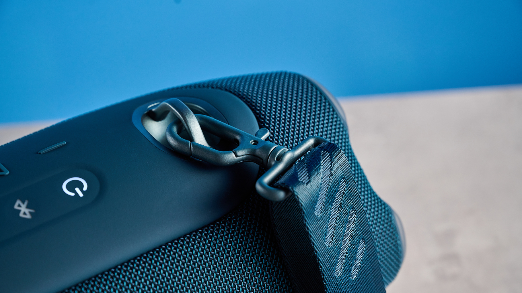the JBL Xtreme 5 bluetooth speaker in blue shown with the rugged carry strap and buttons
