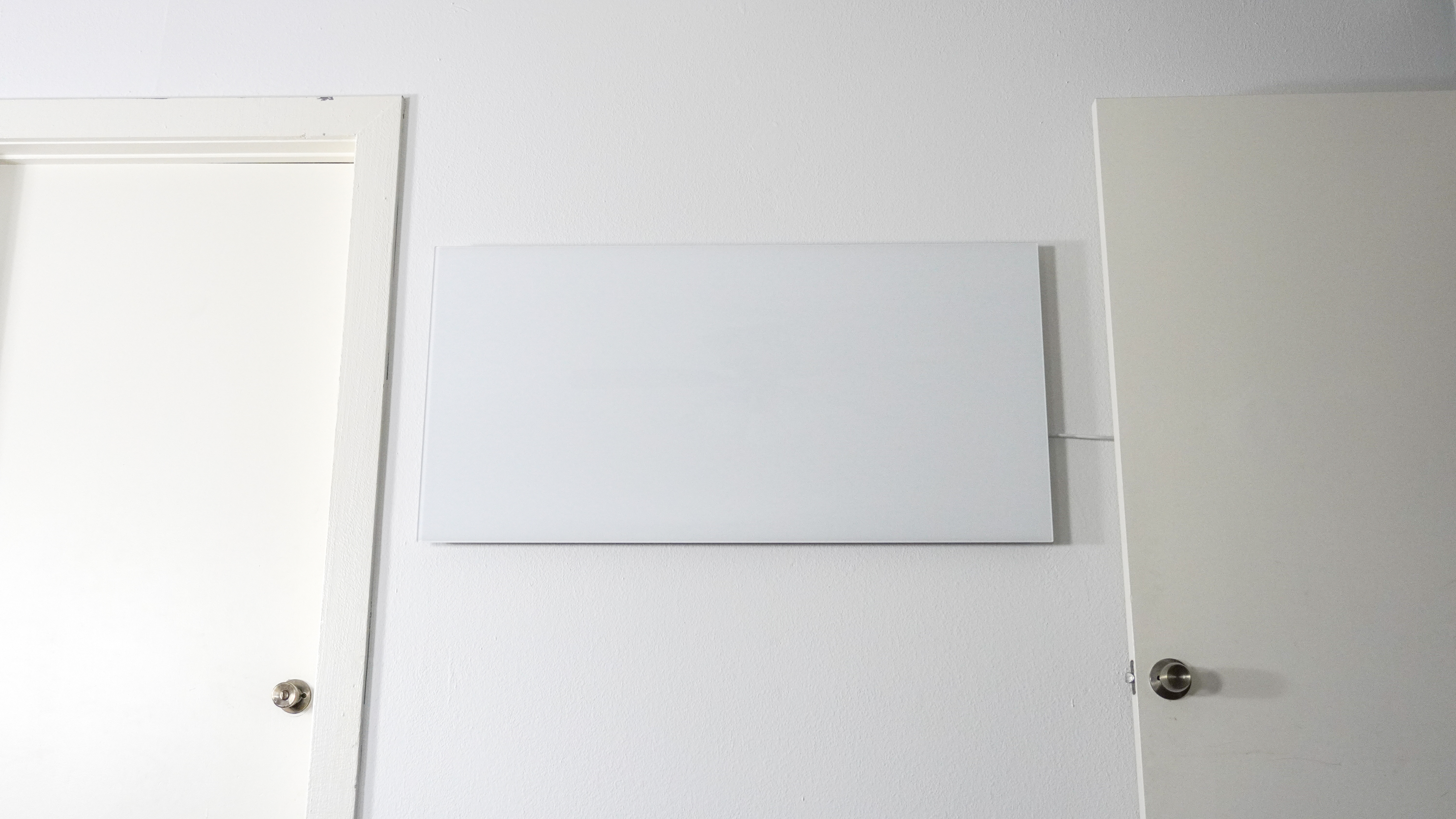 A wide shot of the Boldr Kelvin infrared heater mounted on a wall between two doors