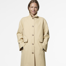 Model wearing a Hobbs butter yellow parka coat and gold round earings