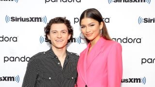 Tom Holland and Zendaya smiling together at a Town Hall to promote Spider-Man.