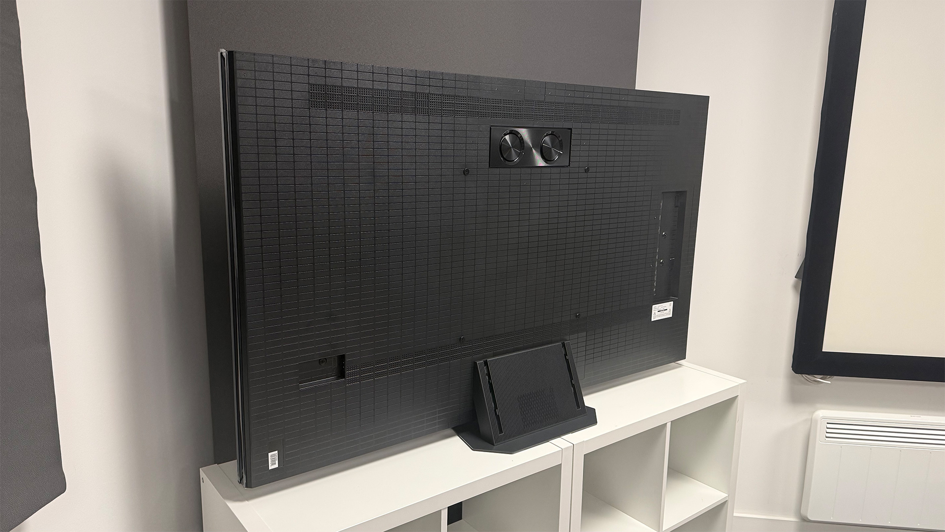 The 65-inch Hisense UR9 RGB Mini LED TV, photographed on a white, wooden unit. On the screen is a still from Netflix documentary, The Dinosaurs.
