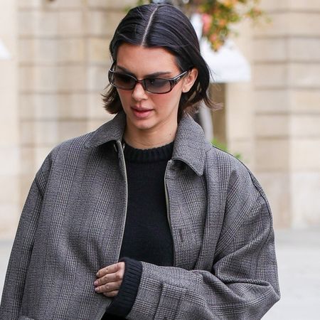 Kendall Jenner in Paris wearing a gray car coat, black sweater, jeans, and black ballet pumps in March 2025.