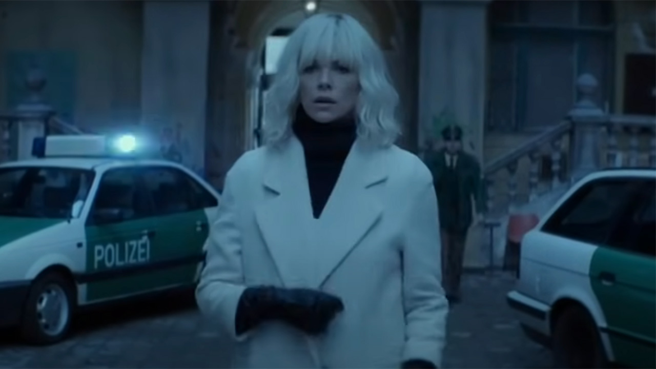 Charlize Theron in cream coat and black and white blazer, boots Atomic Blonde kitchen scene.