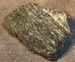 Ökölnyi méretű minta az Acasta gneiszekből, a Kanada északnyugati részén található kőzetekből, amelyek a Föld legrégebbi ismert kőzeteit alkotják.