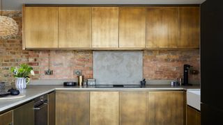 industrial contemporary kitchen with exposed brick walls and brushed metallic cabinets to show one of the key kitchen trends 2023 for metallic touches