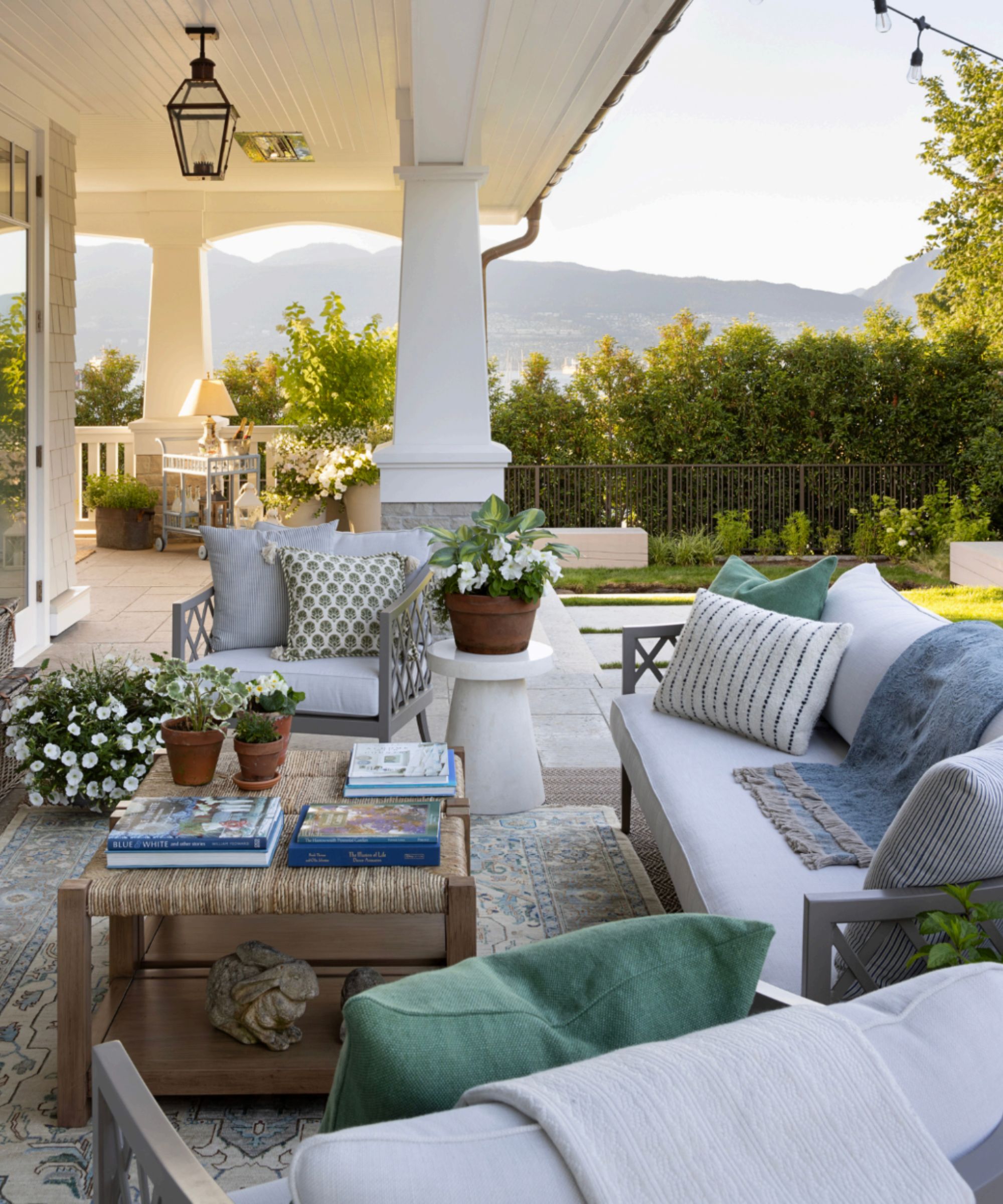 Outdoor living area on a veranda with a white green and blue palette, terracotta plant pots and an outdoor rug