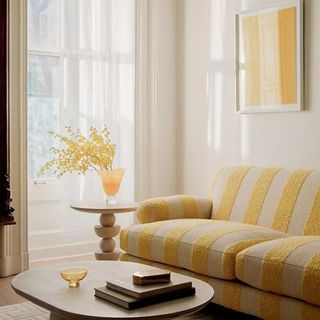 A yellow striped sofa with a coffee table in a bright living room