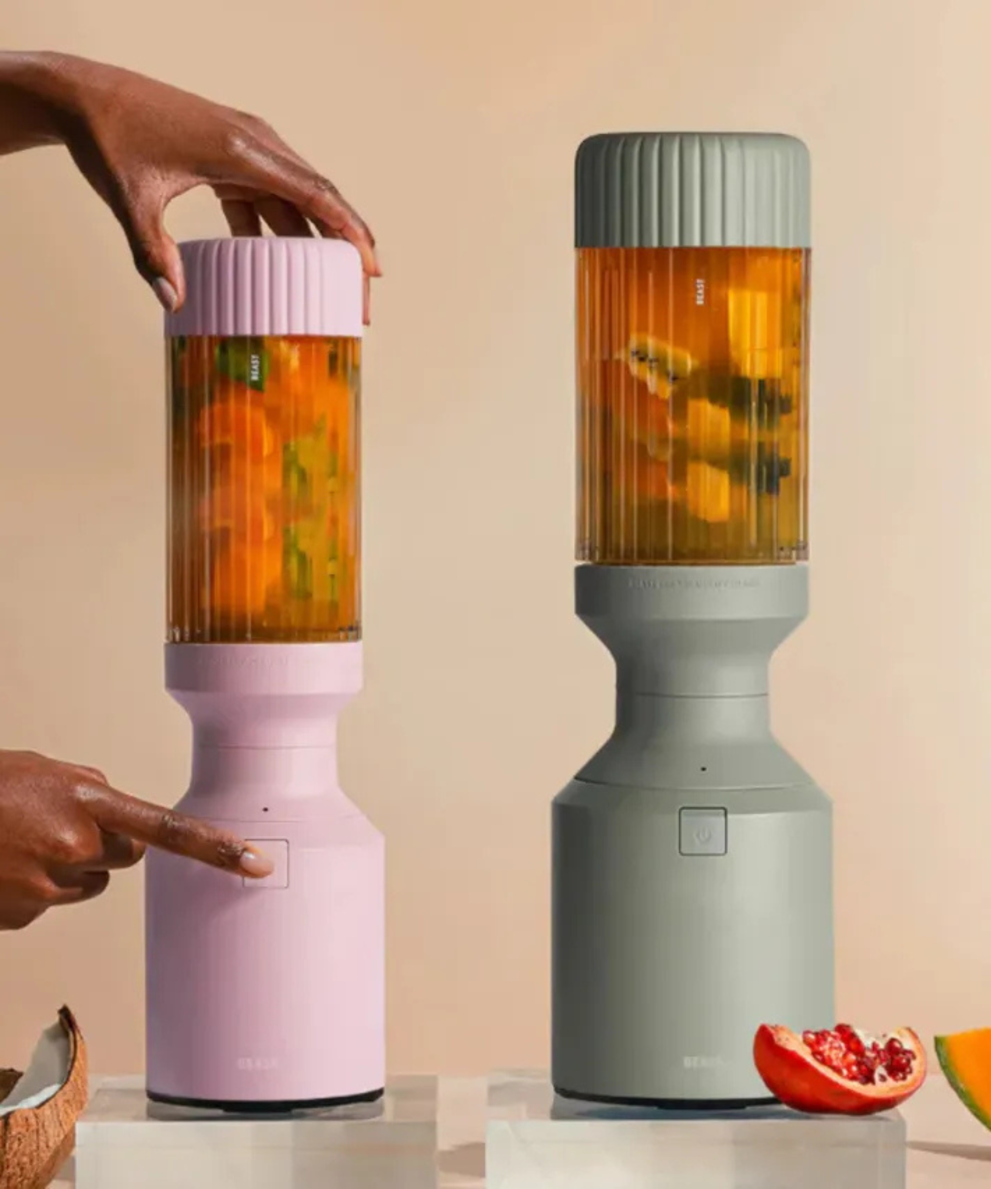 Two Beast blenders in mint and pink, blending tropical smoothies against a pale orange background