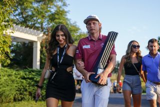 Cameron Smith and his wife walk with a LIV Golf trophy