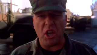 Dean Norris looking at the camera and yelling in army fatigues in NCIS