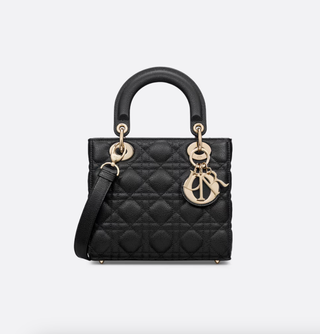 a black lady dior bag in front of a plain backdrop