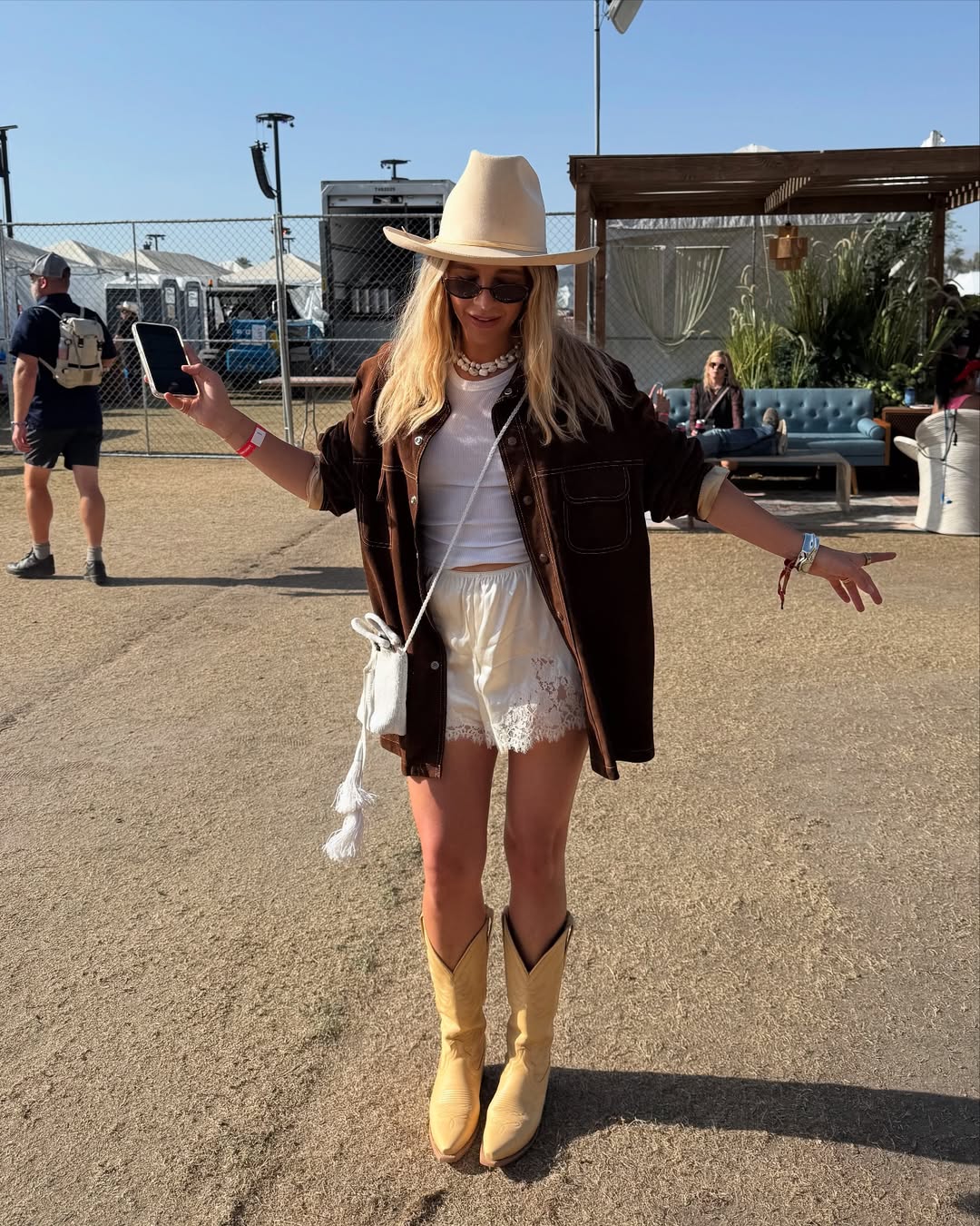 @ashbegash wears cream silk shorts, suede jacket and cowboy boots to festival