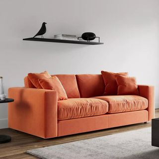 An orange sofa with orange cushions in a grey living room