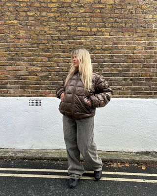 Woman wearing brown puffer and black jeans.