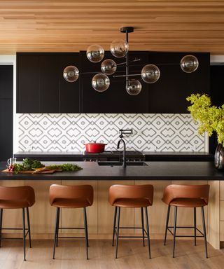 can you fit an island in a galley kitchen, black and wood kitchen with bar stools, graphic style backsplash, black countertops and wall cabinets