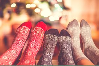 An image of three pairs of feet wearing Christmas socks