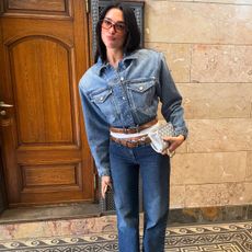 Dua Lipa wearing a denim jacket, jeans, and two belts