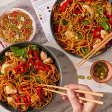 Two bowls of stir fry and recipe card on marble counter